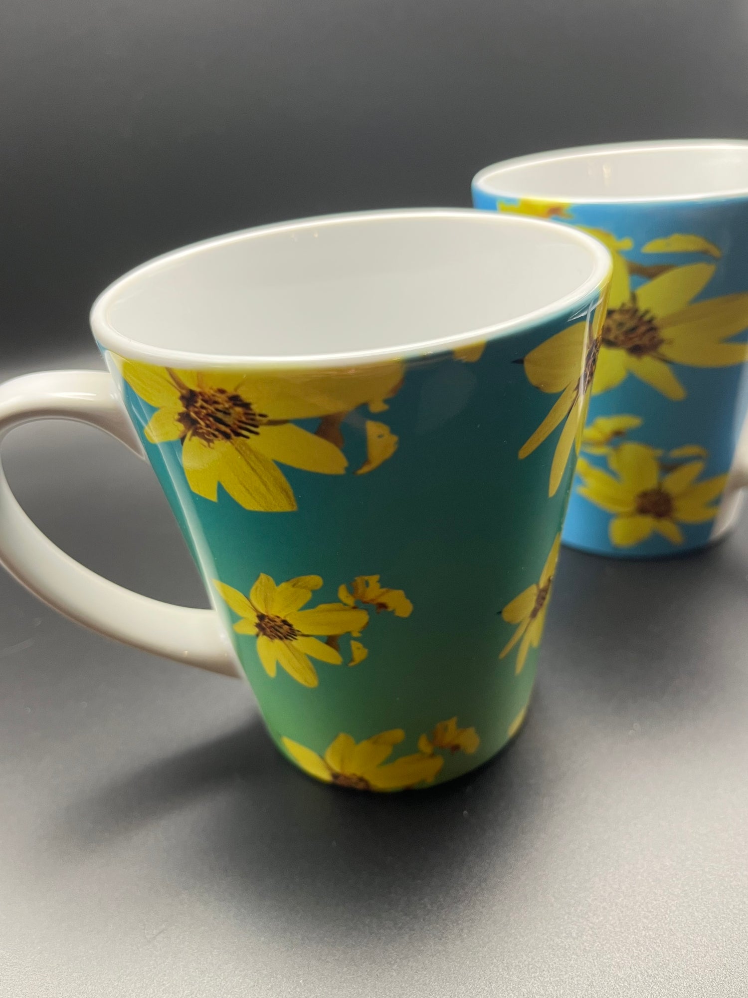 Four floral latte mugs on a festive table.