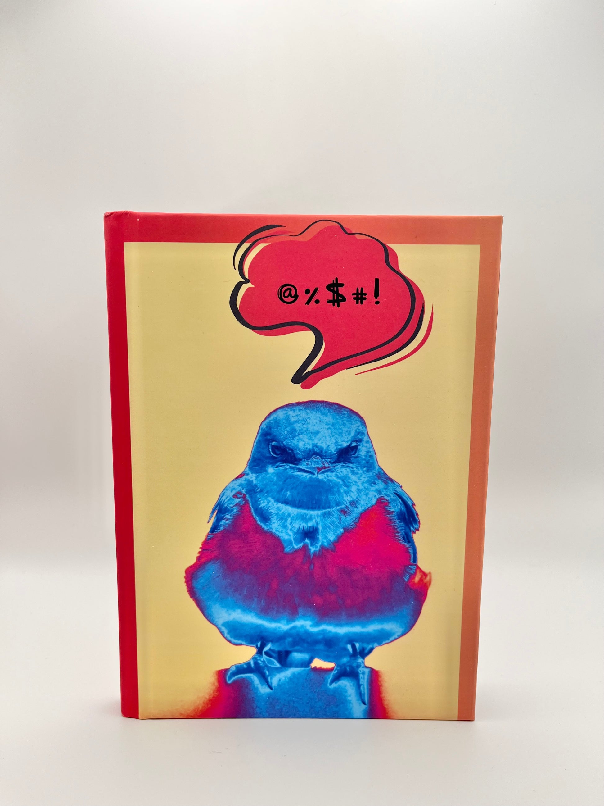 Notebook with a blue bird illustration and colorful speech bubble on a yellow cover.
