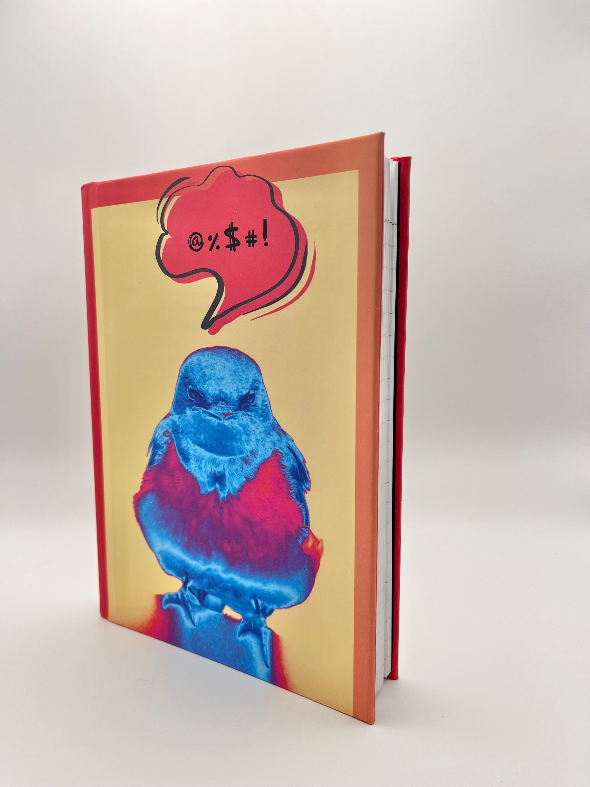 Notebook with a colorful bird design and a red speech bubble on a white background