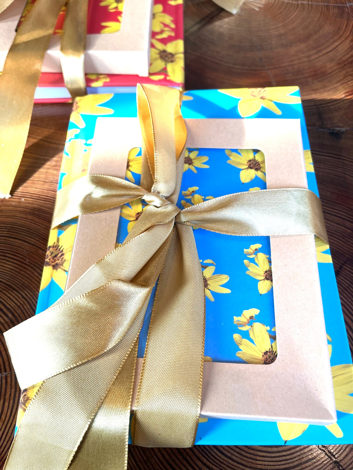 Gift box with floral design and gold ribbon on a wooden surface