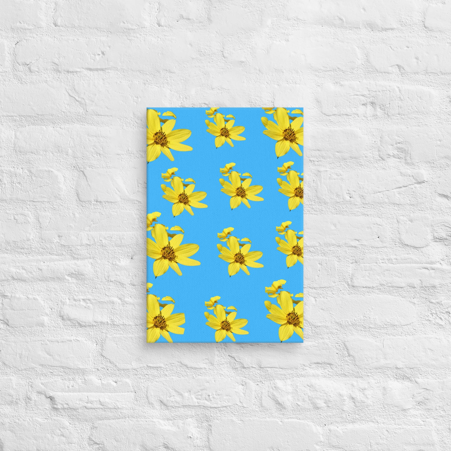 Canvas print with yellow flower pattern on blue background against a textured white wall.