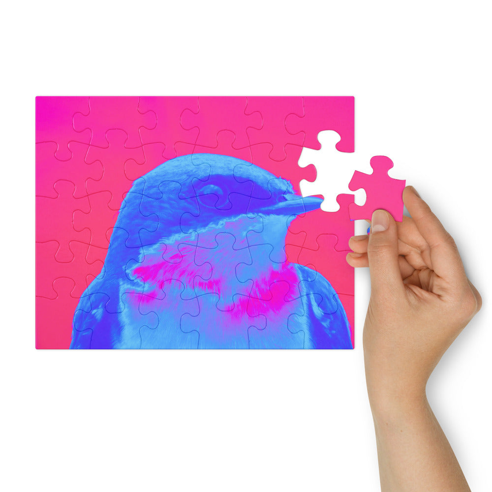 Jigsaw puzzle with a blue and pink bird design, held by a hand.