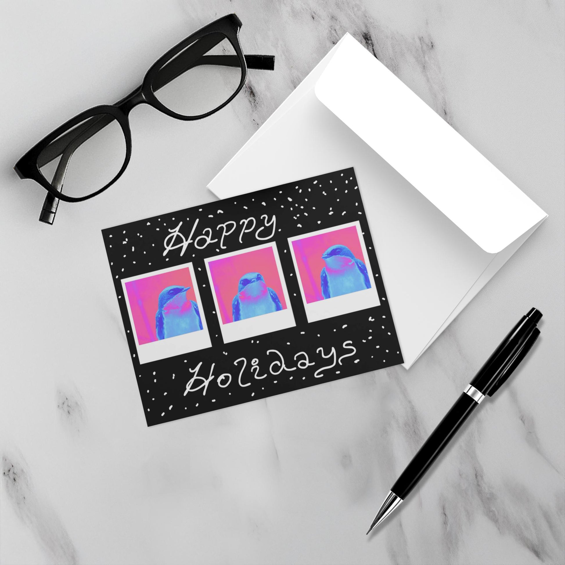 Greeting card with 'Happy Holidays' text and tree swallow illustrations on a marble surface with glasses and a pen. 