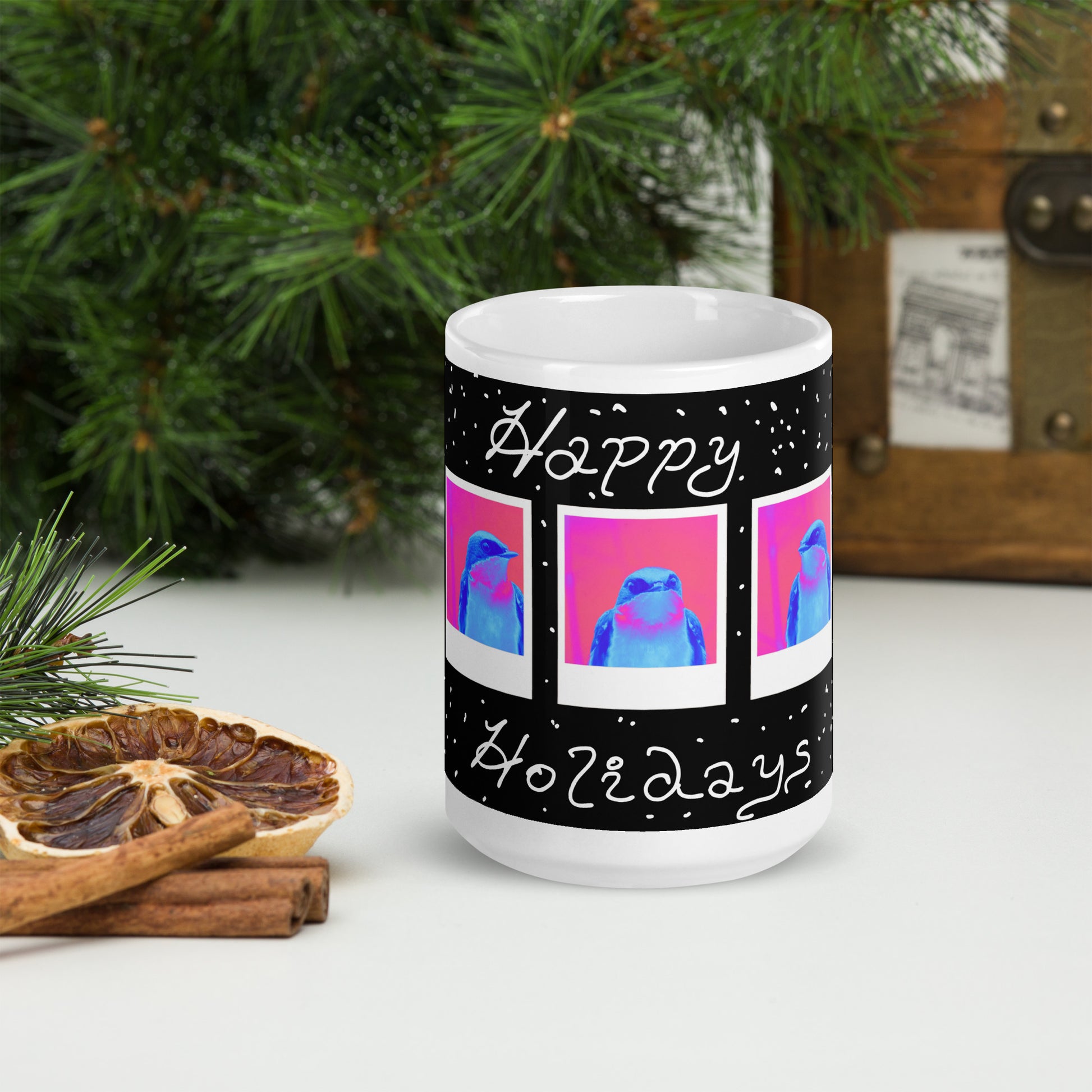 Mug with 'Happy Holidays' design featuring colorful birds, placed on a surface with decorative elements.
