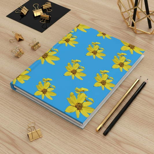 Yellow flowers on blue journal on light wood desk